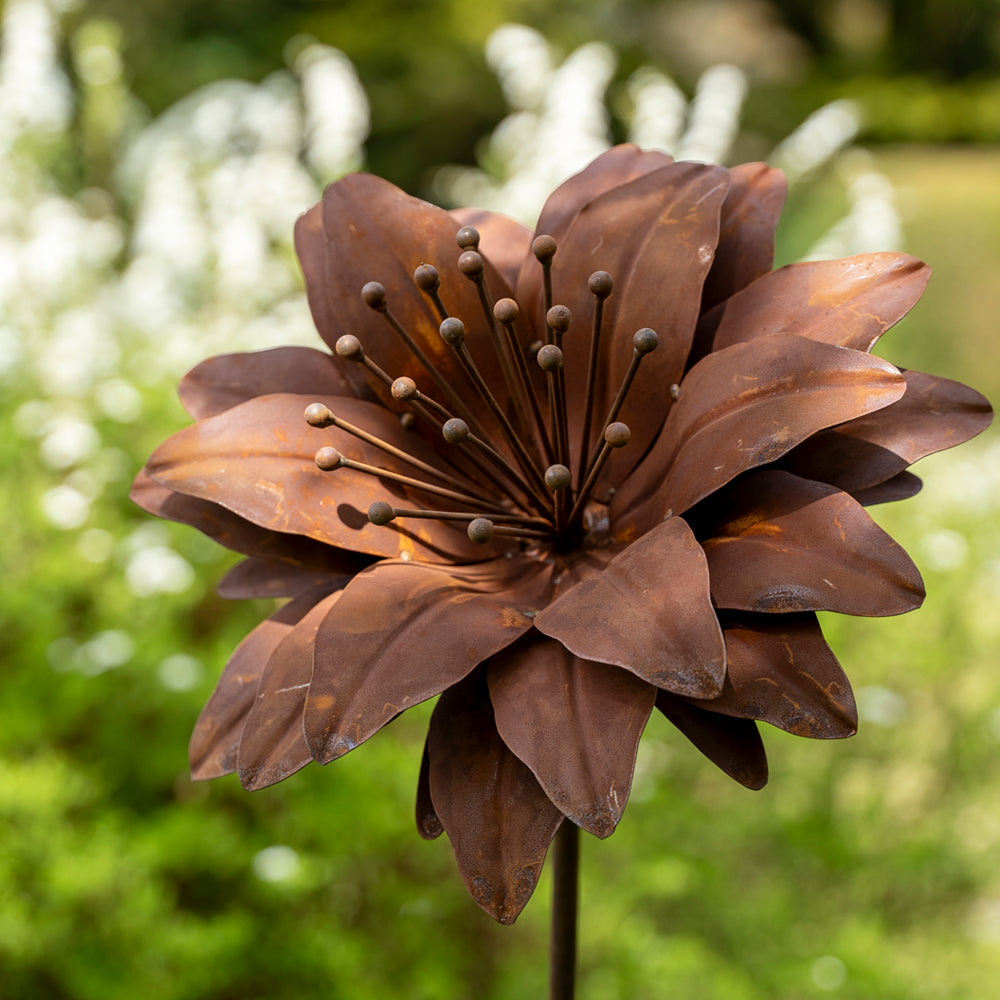 Rust-colored metal flower sculpture against a blurred green background