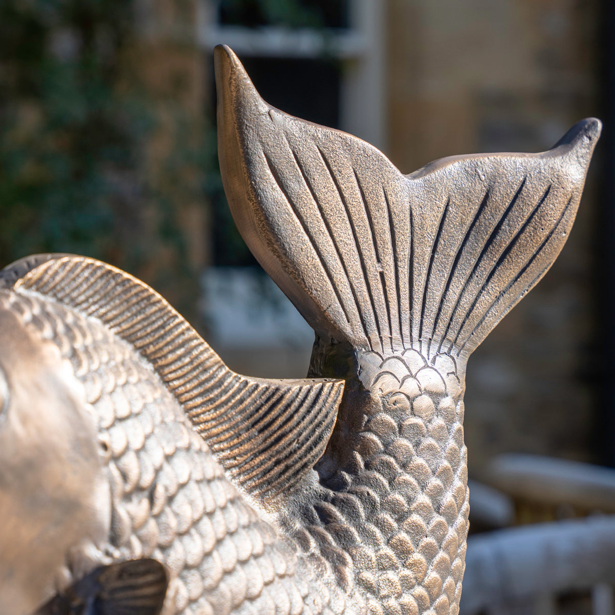 Close-up of a bronze fish sculpture with detailed scales and tail.