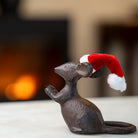 Decorative mouse figurine wearing a Santa hat with a warm glow in the background