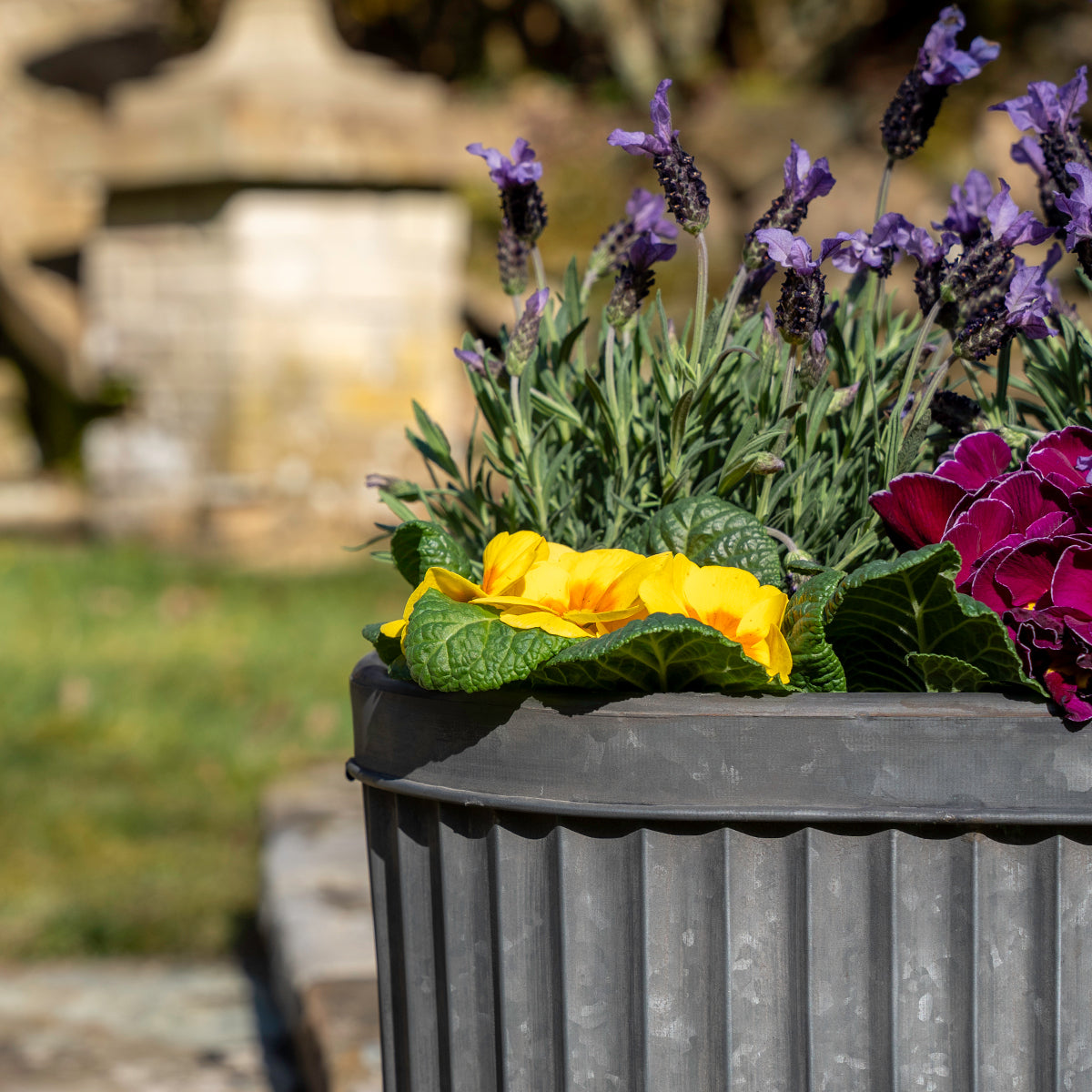 Floral arrangement in a corrugated metal container with a blurred natural background