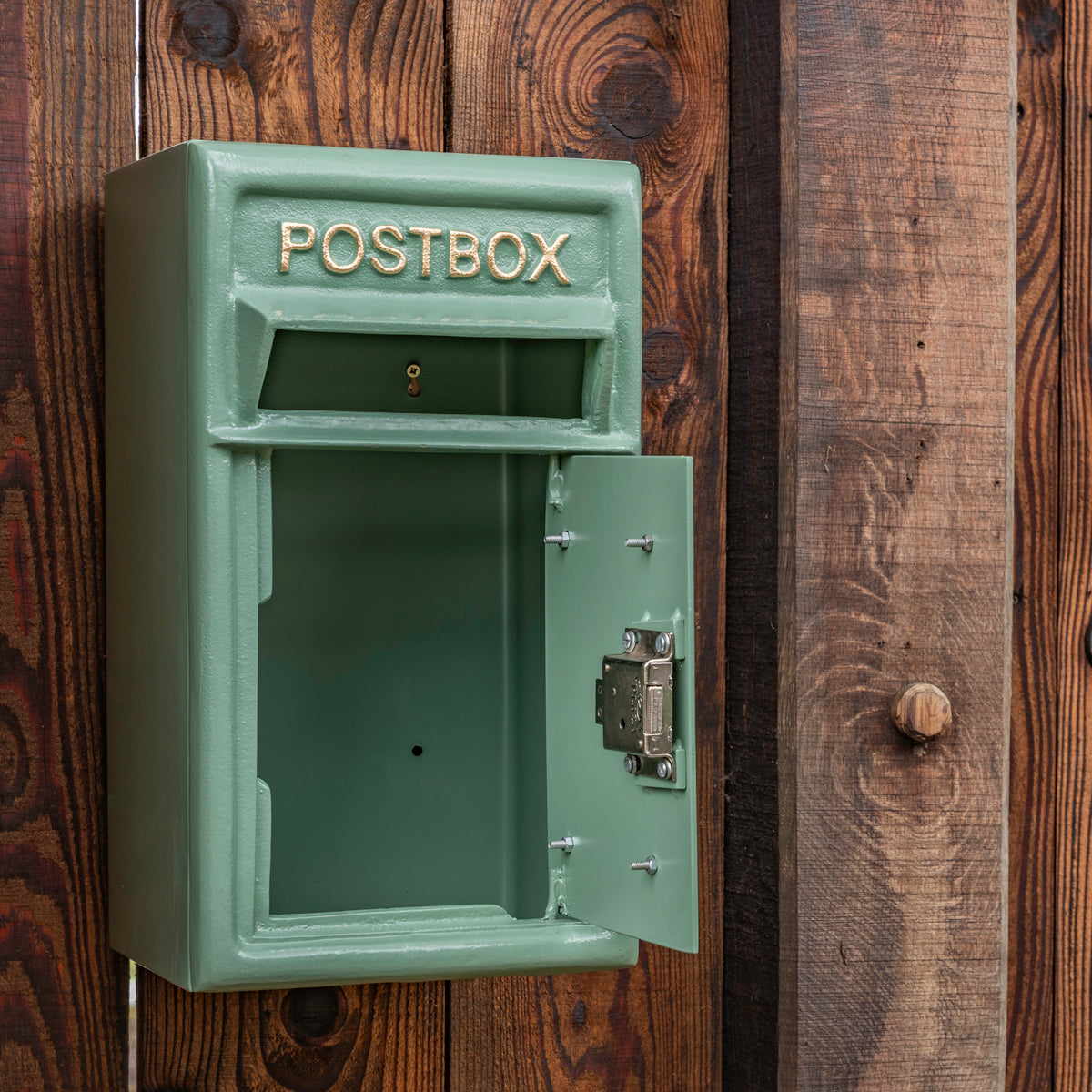 Green postbox mounted on a wooden wall