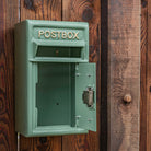Green postbox mounted on a wooden wall