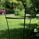 Black metal plant stand on a grassy background