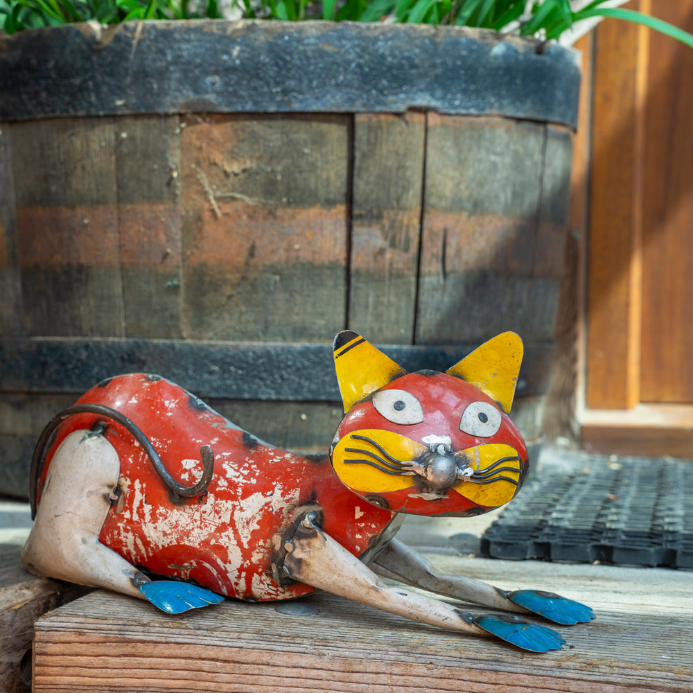Red and yellow cat figurine on a wooden surface with a rustic background